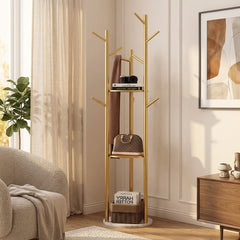 Gold tree coat rack with a white marble-look base in a living room with a scarf on a branch, a bag on a shelf and a basket