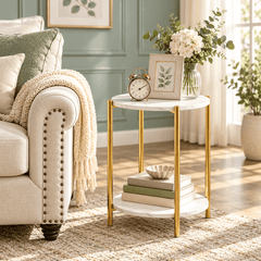 Round two tier gold leg side table beside a cream sofa holding a clock, a framed print and flowers on the top shelf